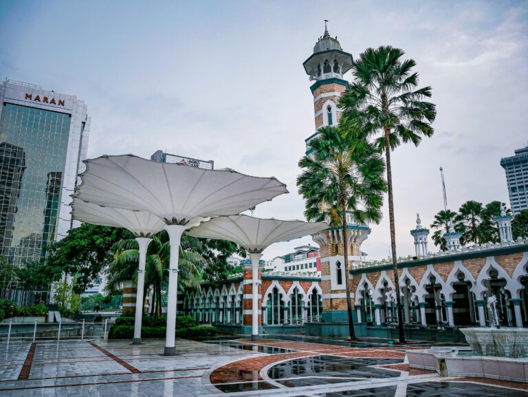 View of Jamek Mosque with lush palm trees and modern architectural elements in Kuala Lumpur, Malaysia.