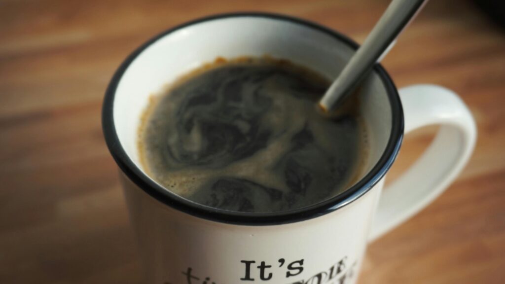 A close-up shot of hot black coffee in a white mug with a spoon, perfect for morning refreshment.
