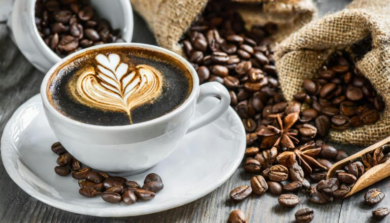A beautifully decorated cappuccino with latte art surrounded by coffee beans on rustic background.