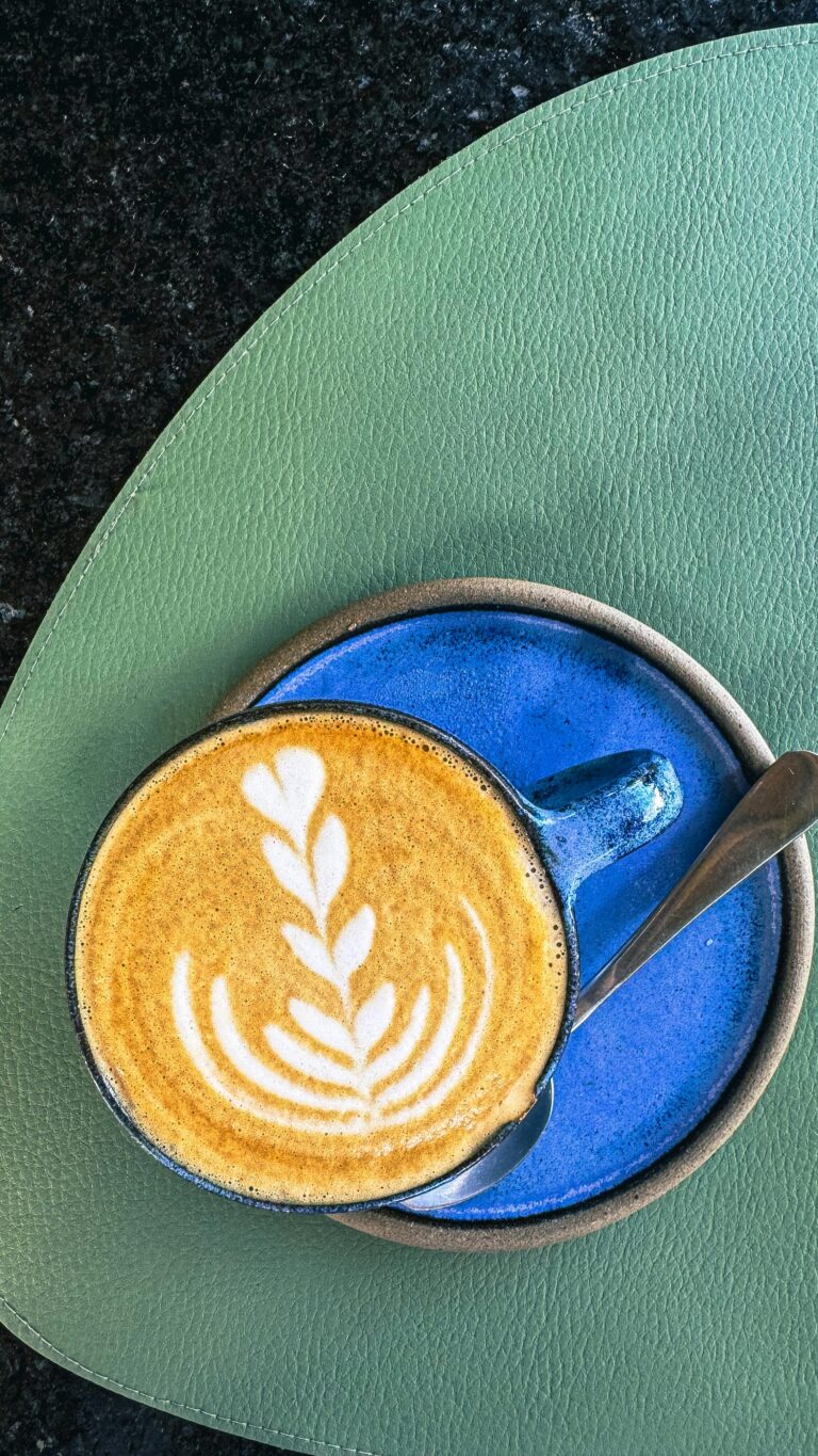Top-down view of a latte with intricate leaf art on a vibrant background, perfect for coffee enthusiasts.