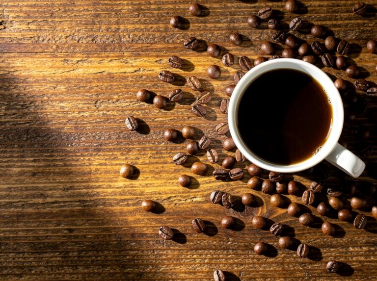 Coffee cup and beans on wooden table, creating a cozy autumn vibe.