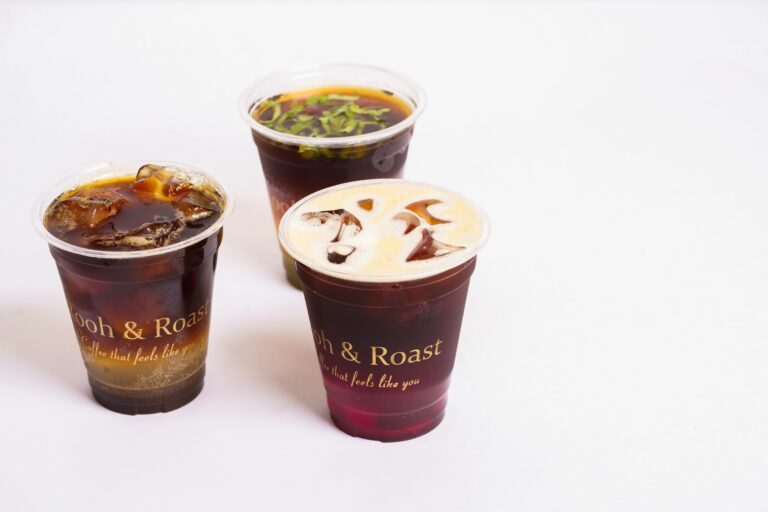 Three cold brew coffee drinks in clear cups with ice over a white background.