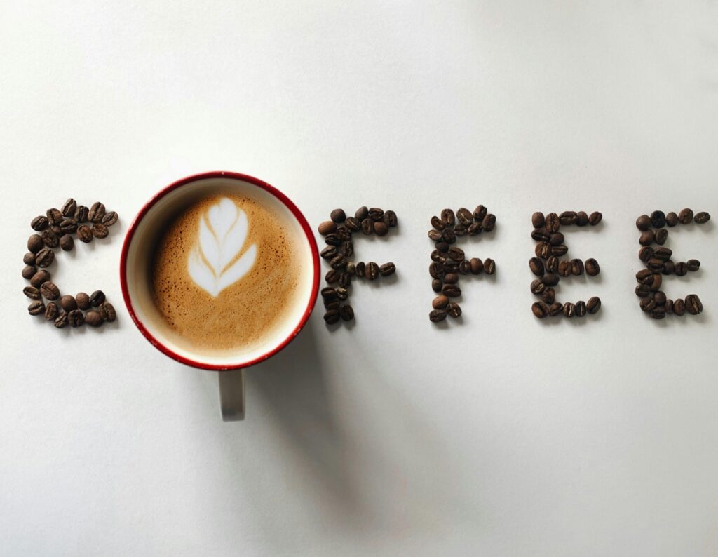 Flat lay of coffee latte with beans spelling COFFEE. Perfect copy space for beverage themes.