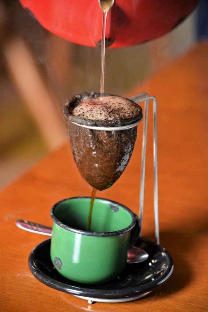 Close-up of traditional Brazilian coffee being brewed with cloth filter into a green cup.